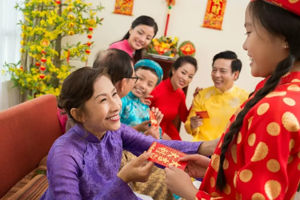 vietnamvisaexpress - indoor shot of a Vietnamese family in traditional áo dài, grandparents handing red envelopes (lì xì) to smiling children, realistic faces, hands and envelopes clearly visible, joyful atmosphere